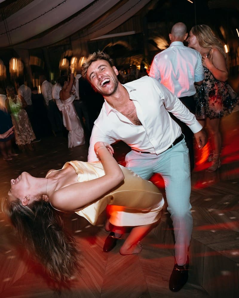 Guests dancing and laughing on a dance floor at a wedding party